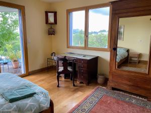 a bedroom with a desk and a bed and a window at Poulou Pyrénées in Gelos
