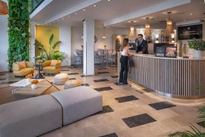 a man and woman standing at a bar in a lobby at Hotel SERHS Del Port in Barcelona