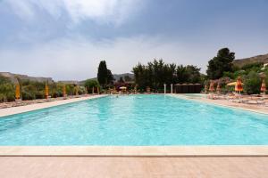 a large swimming pool with chairs and umbrellas at Villa Margi in Scopello
