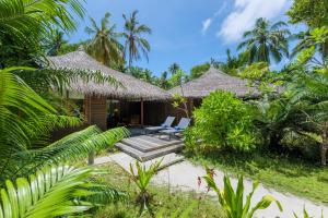a resort with two chairs and a porch with palm trees at Kuramathi Maldives in Rasdu