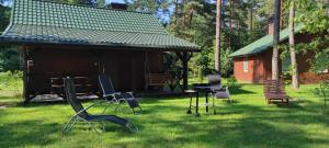 a group of chairs in the grass in front of a cabin at Domki Nad Tanwią in Susiec