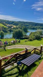 a wooden bench sitting on top of a field with a lake at Dobra Miejscówka Domki nad Jeziorem Solińskim Jacuzzi 60 m od plaży 504-978-418 in Zawóz