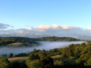 a misty valley with trees and mountains in the background at Poulou Pyrénées in Gelos