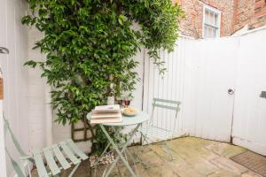 a table and chairs on a patio with a climbing plant at Oriel Cottage, Aldeburgh in Aldeburgh