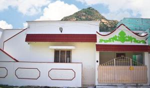 a white house with a mountain in the background at Shree Anugraha Home Stays in Tiruvannāmalai