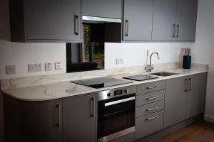 a kitchen with white cabinets and a sink and a stove at Drumfin Cottage in Elgin