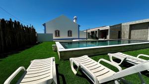 two white chairs and a swimming pool in a yard at OceanLand - Santa Cruz in Santa Cruz