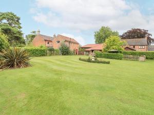 a large yard with a house in the background at The Barn in Ashill