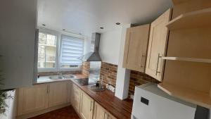 a kitchen with wooden cabinets and a sink and a window at Appartement spacieux à Caen 65 m² avec balcon vue sur la ville in Caen