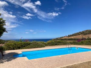 a blue swimming pool with the ocean in the background at Abba Sixty - View, Pool & Parking - 200mt Sea in Tertenìa
