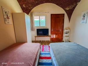 a bedroom with a bed and a tv and a window at Sahure Pyramid View Inn in Cairo