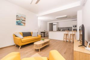a living room with a yellow couch and a kitchen at Aparto Almi in Moraira