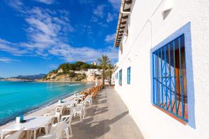 a row of tables and chairs next to the ocean at Aparto Almi in Moraira