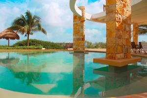 einen Pool in einem Resort mit einer Palme in der Unterkunft Corcomoran Luxury beachfront house in Telchac Puerto