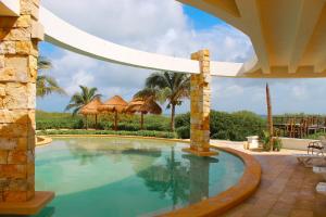 a swimming pool with umbrellas in a resort at Corcomoran Luxury beachfront house in Telchac Puerto
