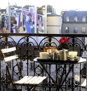 a table with coffee cups and bread on a balcony at Hôtel Odessa Montparnasse in Paris