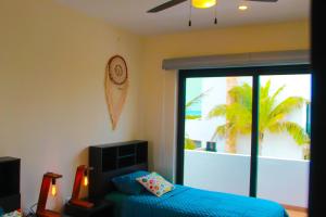 ein Schlafzimmer mit einem blauen Bett und einer Glasschiebetür in der Unterkunft Corcomoran Luxury beachfront house in Telchac Puerto + 39 Fotos
