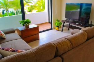 ein Wohnzimmer mit Couch und Flachbildfernseher in der Unterkunft Corcomoran Luxury beachfront house in Telchac Puerto