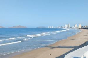 a view of the beach with buildings in the background at Olímpica - Departamento Arcoíris - 5 Min Malecón in Mazatlán