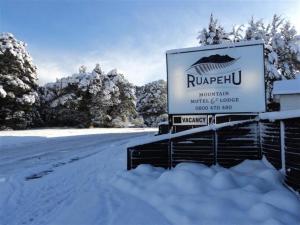 a sign in the snow next to a snowy road at Ruapehu Mountain Motel & Lodge in Ohakune