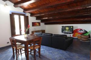 a living room with a couch and a table and a television at Case Vacanze Casa Romana in Lascari