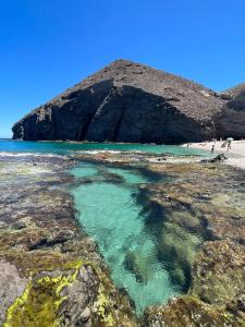 a beach with blue water and people on the beach w obiekcie El Cortijillo w mieście Almería +34 zdjęcia