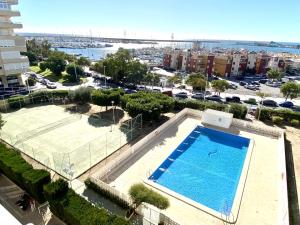 a swimming pool and a tennis court in a city at Luxury apartment with sea view Puerto Torrevieja in Torrevieja