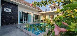 a house with a swimming pool in front of a house at Aranya pool villa in Ban Phu Yai