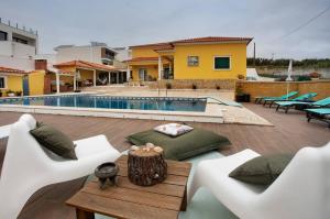 a patio with white chairs and a pool at Porto Dinheiro Beach I in Lourinhã