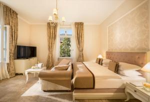 a bedroom with a bed and a couch and a tv at Hotel Kvarner - Liburnia in Opatija