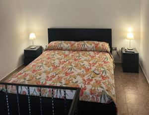 a bedroom with a bed with a floral bedspread and two lamps at B&B Mariagrazia in Albori