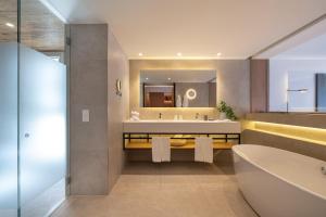 a bathroom with a tub and a large mirror at Onyria Quinta da Marinha Hotel in Cascais