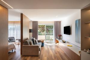 a living room with a couch and a tv at Onyria Quinta da Marinha Hotel in Cascais