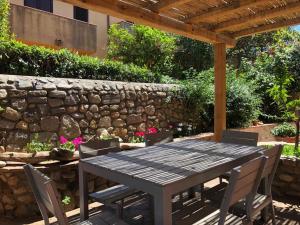 a wooden table with chairs and a stone wall at Alloro 6 in Marciana Marina