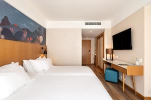 a hotel room with a white bed and a television at Onyria Quinta da Marinha Hotel in Cascais