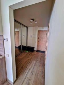 Habitación vacía con espejo grande y suelo de madera. en Apartamentai SMILGA, en Klaipėda