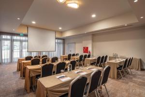 a conference room with tables and chairs and a screen at Onyria Quinta da Marinha Hotel in Cascais