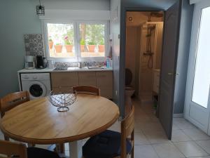 a kitchen with a wooden table with chairs and a sink at Studio de la pinède in Nissan-lez-Enserune