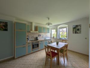 a kitchen with blue cabinets and a table with chairs at Ferienwohnung grünes Haus Colditz in Colditz
