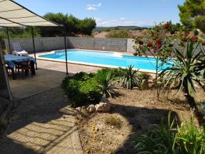 a swimming pool in a garden with a table and an umbrella at Studio de la pinède in Nissan-lez-Enserune