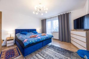 a bedroom with a blue bed and a flat screen tv at Apartament u Sabiny i Stanleya in Bukowina Tatrzańska
