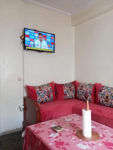 a living room with a red couch and a tv at Elbernoussi in Casablanca
