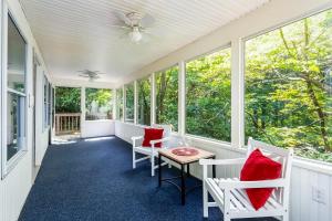 a porch with white chairs and a table with red pillows at Shenandoah mountain cottage w hot tub & fire pit in Front Royal
