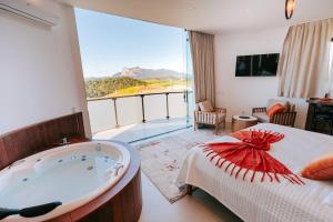 a hotel room with a tub and a large window at Chalés Rota dos Lagos in Pedra Azul