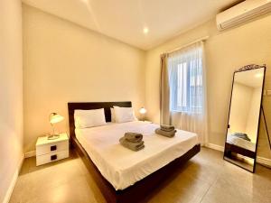 a bedroom with a bed and a mirror and a window at Charming flat off the sea front in Il-Gżira