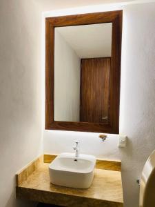 a bathroom with a white sink and a mirror at Hotel Villas Ema in Zihuatanejo