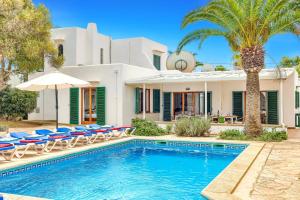 a house with a swimming pool with chairs and an umbrella at Villa Rigo by Villa Plus in Cala D'or