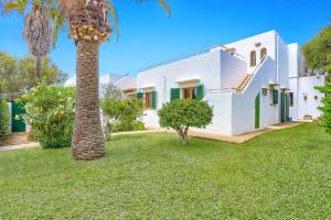a palm tree in front of a white house at Villa Rigo by Villa Plus in Cala D'or