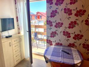 a room with a sliding glass door with a tv and flowers at Kalina in Łeba
