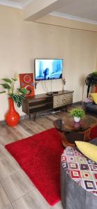 sala de estar con TV y alfombra roja en Kabs Apartment, en Kisumu 9 fotos más